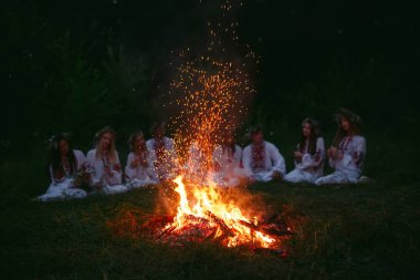 Yaz gecesi. Şenlik ateşi oturan Slav giysili gençler