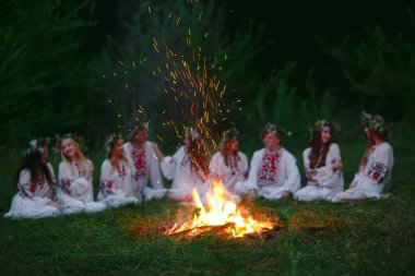 Yaz gecesi. Şenlik ateşi oturan Slav giysili gençler