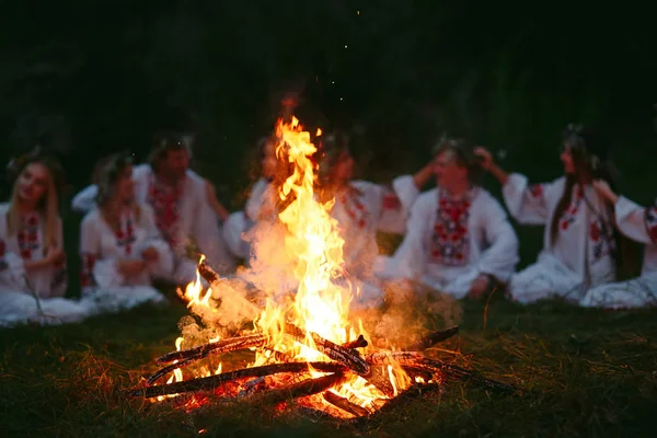 Yaz gecesi. Şenlik ateşi oturan Slav giysili gençler