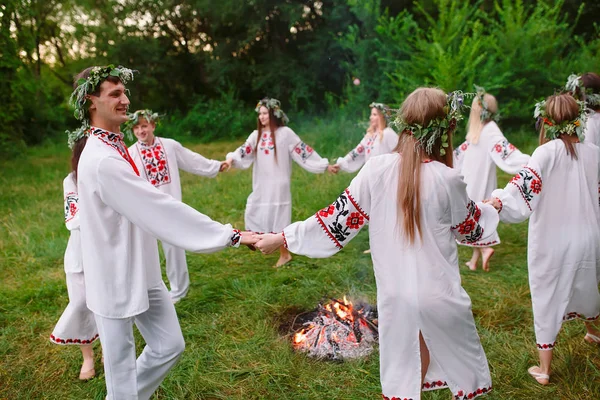 Letní slunovrat. Mladí lidé v slovanských oblečení se točí kolem ohně v období letního slunovratu — Stock fotografie