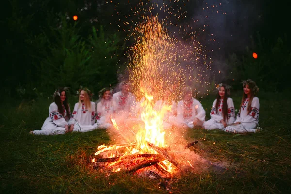 Midsommarnatten. Ungdomar i slaviska kläder sitter nära brasan — Stockfoto