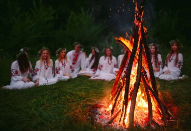 Yaz gecesi. Şenlik ateşi oturan Slav giysili gençler