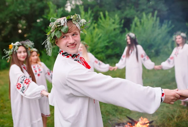 Hochsommer. Junge Leute in slawischer Kleidung drehen sich im Hochsommer um ein Feuer — Stockfoto