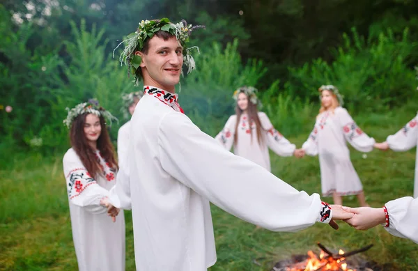 Θερινό ηλιοστάσιο. Νέοι άνθρωποι στην σλαβική ρούχα περιστρέφεται γύρω από μια φωτιά στη Midsummer — Φωτογραφία Αρχείου