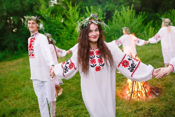 Hochsommer. Junge Leute in slawischer Kleidung drehen sich im Hochsommer um ein Feuer — Stockfoto