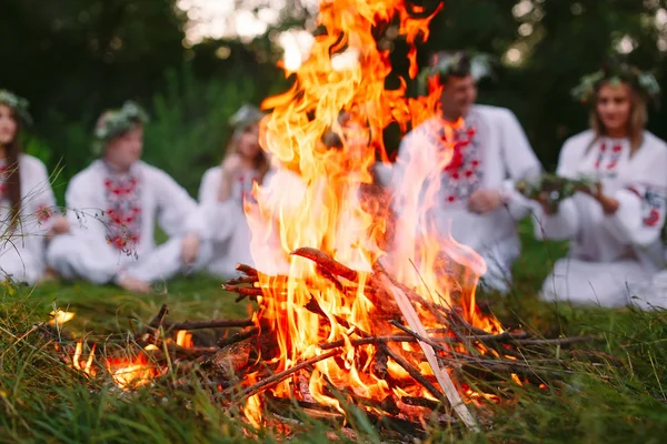 Θερινό ηλιοστάσιο. Νέοι άνθρωποι στην σλαβική ρούχα που κάθεται στο δάσος κοντά στη φωτιά. — Φωτογραφία Αρχείου