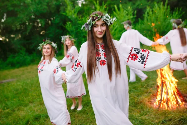 Θερινό ηλιοστάσιο. Νέοι άνθρωποι στην σλαβική ρούχα περιστρέφεται γύρω από μια φωτιά στη Midsummer — Φωτογραφία Αρχείου