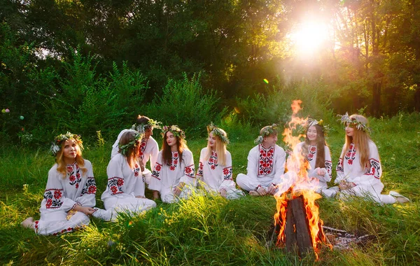 Midsommar. Gruppen av ungdomar av slaviska utseende sitter runt en lägereld. — Stockfoto