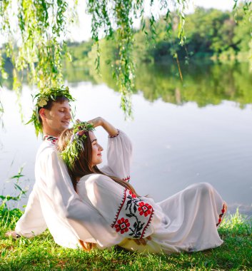 Midsummer. Gölün kıyısında Slav kostümleri genç seven çift. Ivan Kupala Slav tatili.