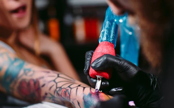 Artista profesional del tatuaje hace un tatuaje en una mano de chicas jóvenes. — Foto de Stock