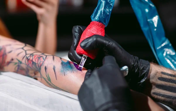 Artista de tatuagem profissional faz uma tatuagem em uma mão de meninas. — Fotografia de Stock