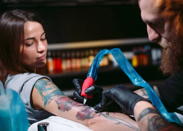 Artista profesional del tatuaje hace un tatuaje en una mano de chicas jóvenes. — Foto de Stock