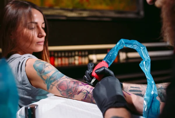 Artista profesional del tatuaje hace un tatuaje en una mano de chicas jóvenes. — Foto de Stock