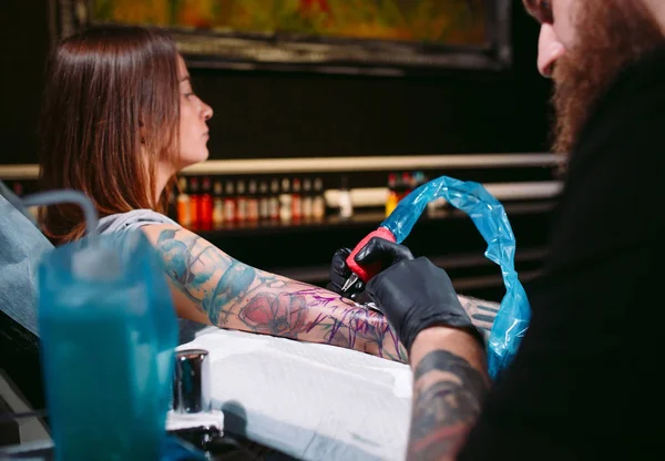 Artista de tatuagem profissional faz uma tatuagem em uma mão de meninas. — Fotografia de Stock