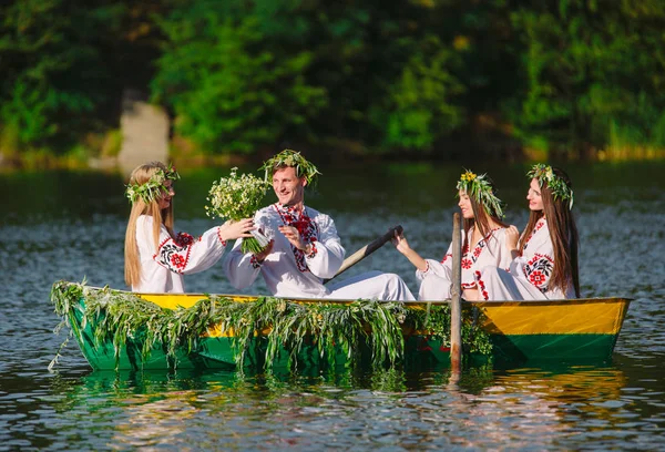 Midsummer. Egy csoport fiatal népviseletben vitorlát egy hajón, amely díszített levelek és növedékek. Ivan Kupala szláv ünnepe — Stock Fotó