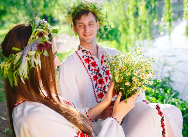 Hochsommer. junges Liebespaar in slawischen Kostümen am Ufer des Sees. slawischer Feiertag von ivan kupala. — Stockfoto