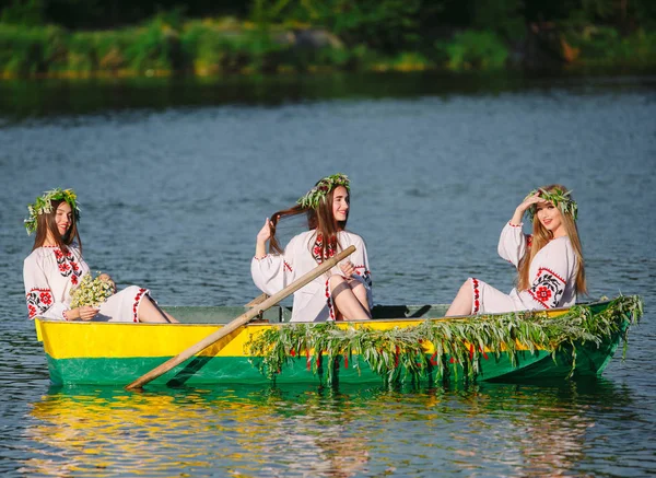 In piena estate. Giovani ragazze in costumi nazionali navigare in una barca che è decorato con foglie e crescite. Vacanza slava di Ivan Kupala . — Foto Stock