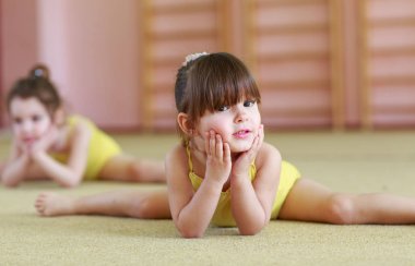 Genç kızlar spor salonunda jimnastik yapıyor.