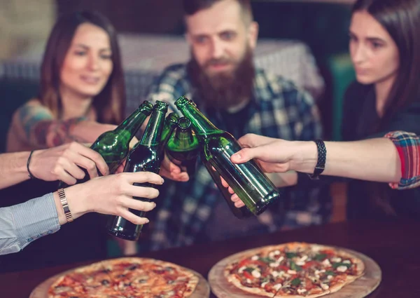 Amigos tomando una copa en un bar, están sentados en una mesa de madera con cervezas y pizza —  Fotos de Stock