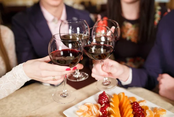 Amigos em um restaurante bebendo vinho tinto . — Fotografia de Stock