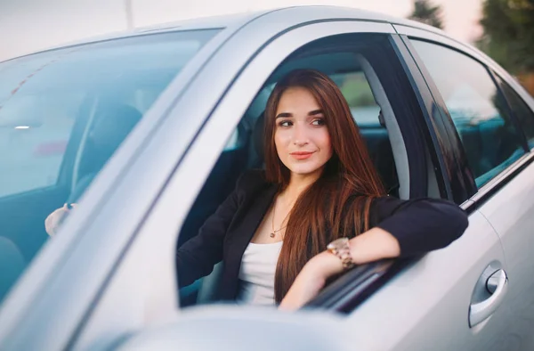 Linda chica morena en el coche. Elegante mujer de negocios conduciendo un coche . — Foto de Stock