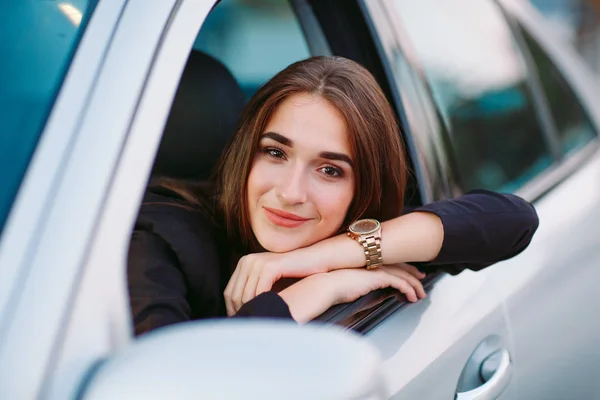 Linda chica morena en el coche. Elegante mujer de negocios conduciendo un coche . — Foto de Stock