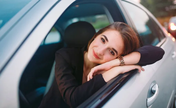 Linda chica morena en el coche. Elegante mujer de negocios conduciendo un coche . — Foto de Stock