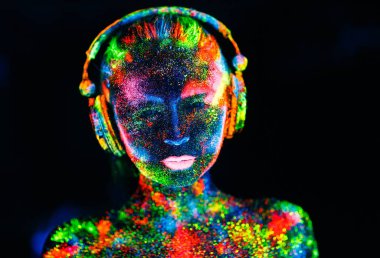 Kavram. Dj destesini boyayan bir kızın cesedinin üzerinde. Uv renklerde boyanmış yarı çıplak kız