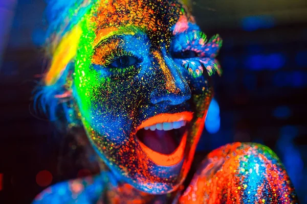 Concepto. La chica sonríe. Retrato de una niña pintada en polvo fluorescente — Foto de Stock
