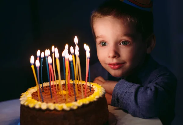 Geburtstag. Ein kleiner Junge bläst Kerzen auf dem Herd aus. — Stockfoto