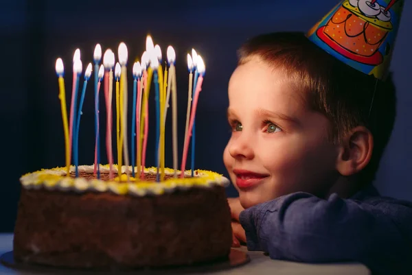 Geburtstag. Ein kleiner Junge bläst Kerzen auf dem Herd aus. — Stockfoto