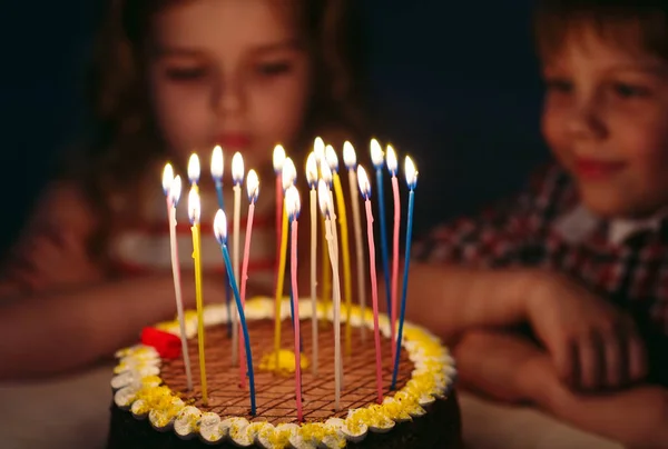 Childrens verjaardag. Kinderen in de buurt van een verjaardagstaart met kaarsen. — Stockfoto