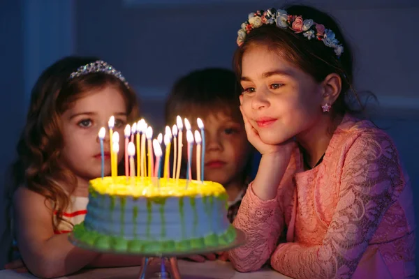 Childrens verjaardag. Kinderen in de buurt van een verjaardagstaart met kaarsen — Stockfoto