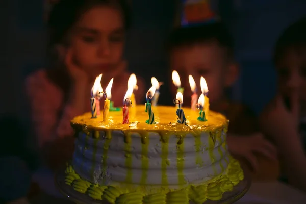 Childrens verjaardag. Kinderen in de buurt van een verjaardagstaart met kaarsen — Stockfoto