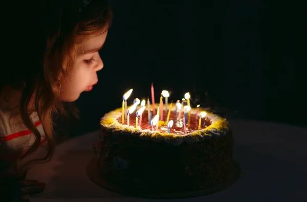 Aniversário. Uma menina doce apaga velas no calcanhar — Fotografia de Stock