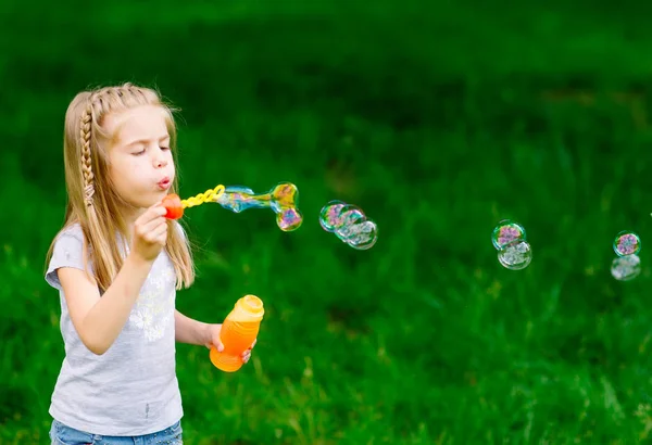 Parkta sabun köpüğüyle oynayan küçük kız.