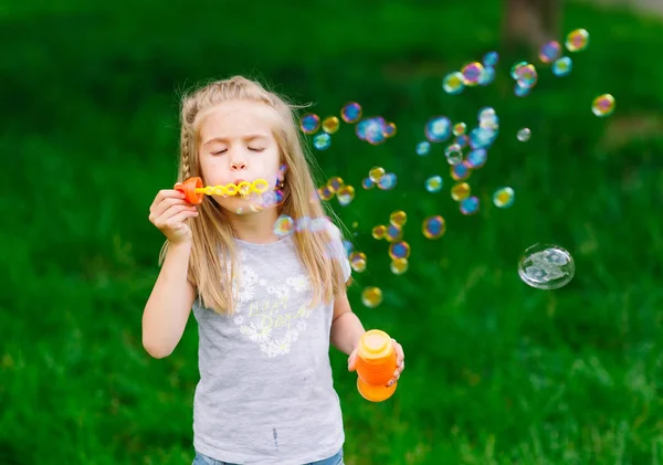 Parkta sabun köpüğüyle oynayan küçük kız.