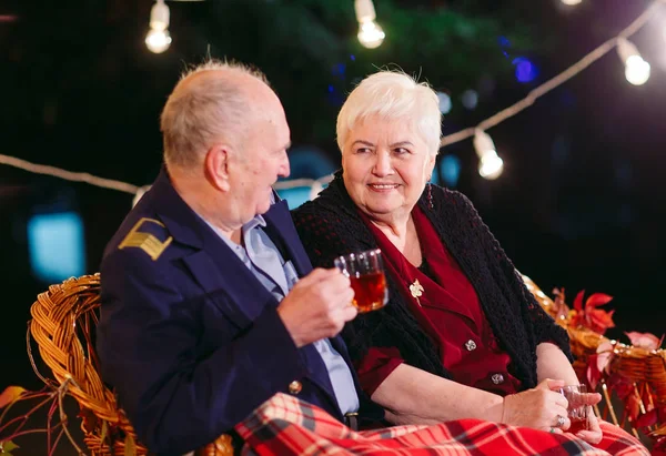 Happy senior couple drinking tea in the evening sitting on the couch — Stock Photo, Image