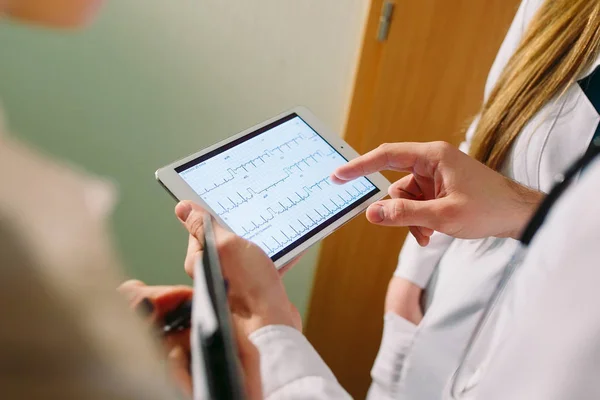 Lékaři diskutují o pacientech kardiogram na tabletu — Stock fotografie