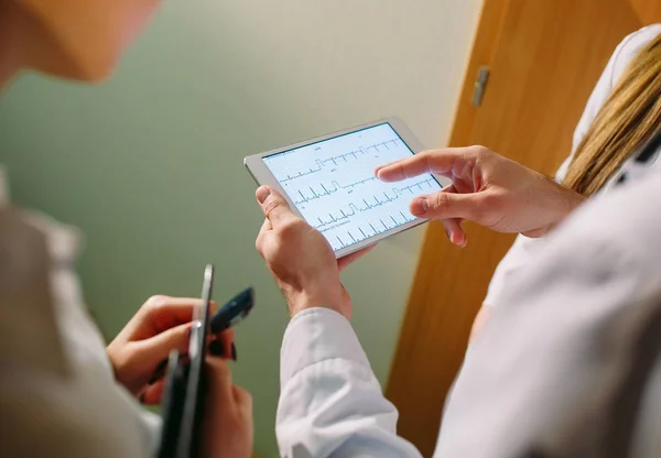 Lékaři diskutují o pacientech kardiogram na tabletu — Stock fotografie