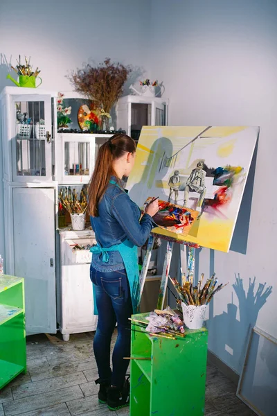 Hermosa chica en un estudio de pintura dibuja un cuadro . — Foto de Stock