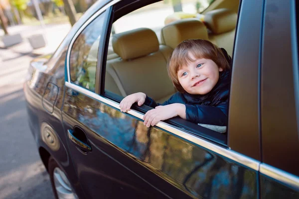 Niño en el coche negro con interior beige . — Foto de Stock