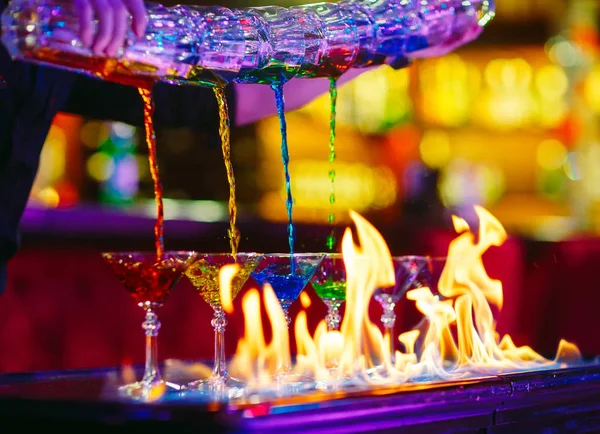 Cantinero Vertiendo Coloridas Bebidas Alcohólicas Vasos Con Fuego Superficie Barra — Foto de Stock