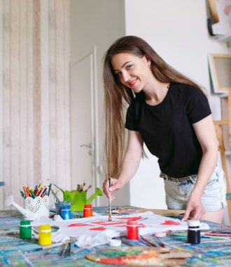 Kıyafet çiziyor. Kız beyaz bir tişört çizer.