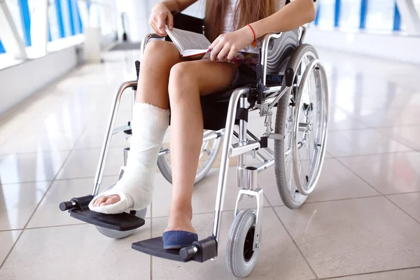 En bok en ung flicka i en rullstol. Patienten i rullstol i en sjukhuskorridor. — Stockfoto