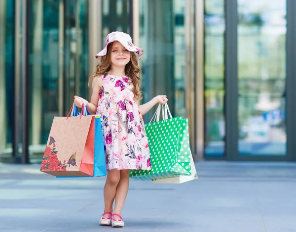 Jolie petite fille en shopping. Portrait d'un enfant avec des sacs à provisions. Faire du shopping. fille — Photo