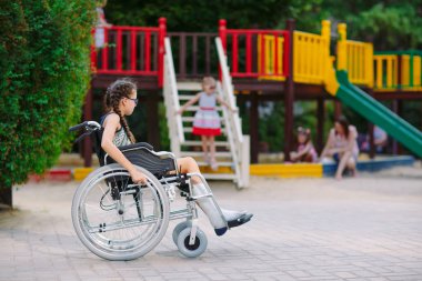 Kırık bir bacak bir kızla Bahçesi önünde tekerlekli sandalyede oturur
