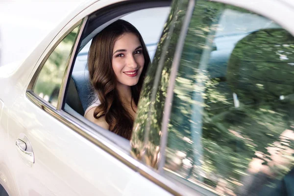 La chica está sentada en el asiento trasero del coche. . — Foto de Stock