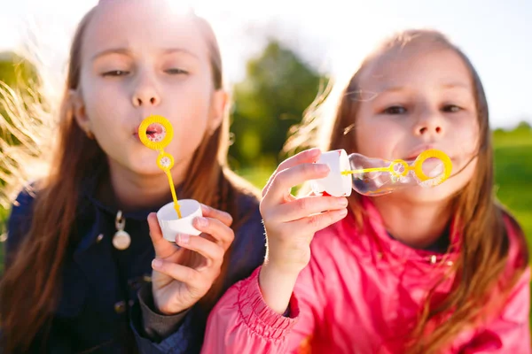 Дівчата грають з мильними бульбашками у весняний час . — стокове фото