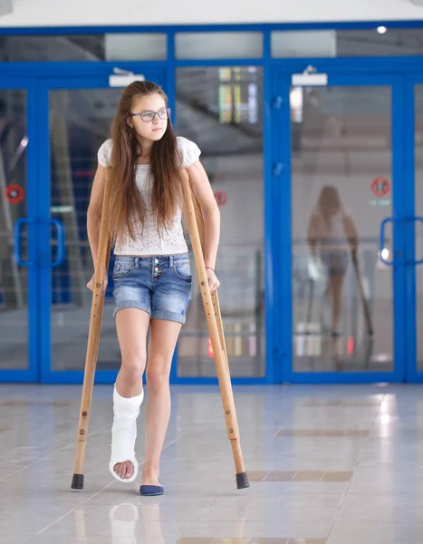 Uma jovem está de muletas no corredor do hospital. — Fotografia de Stock